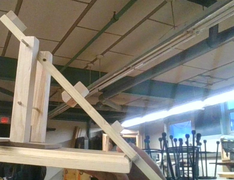 The wooden base and vertical upright that support the arm